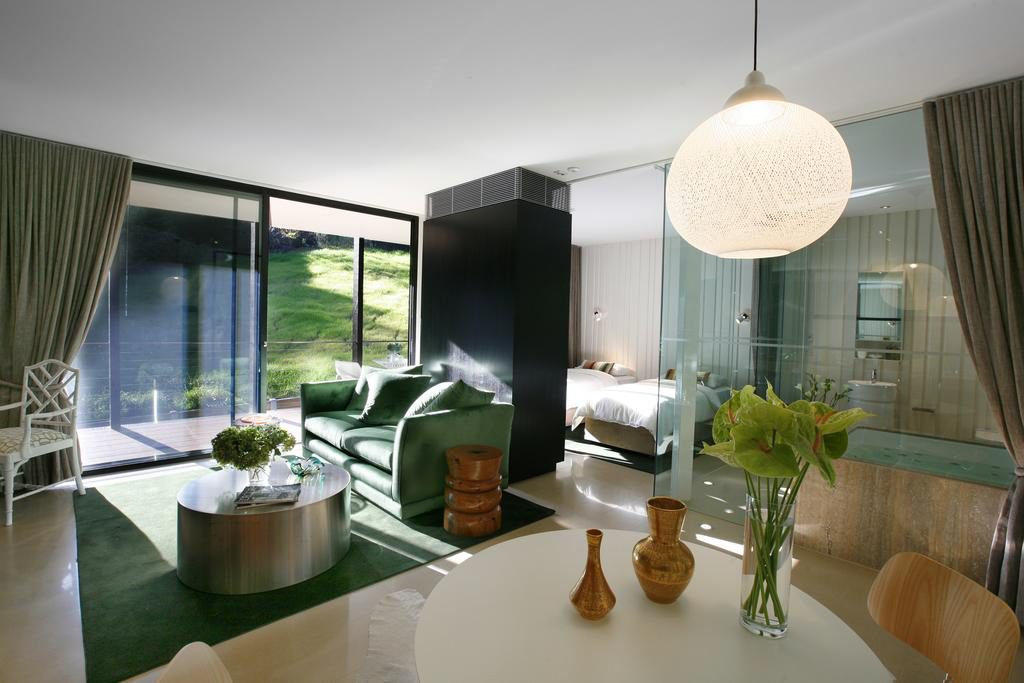 Interior of Green and Beige Decor Villa, View from kitchen dining through lounge room and to balcony with views of lawn. View of King spa and glass floor to ceiling bathroom walls, showing optional twin bed configuration in bedroom.
